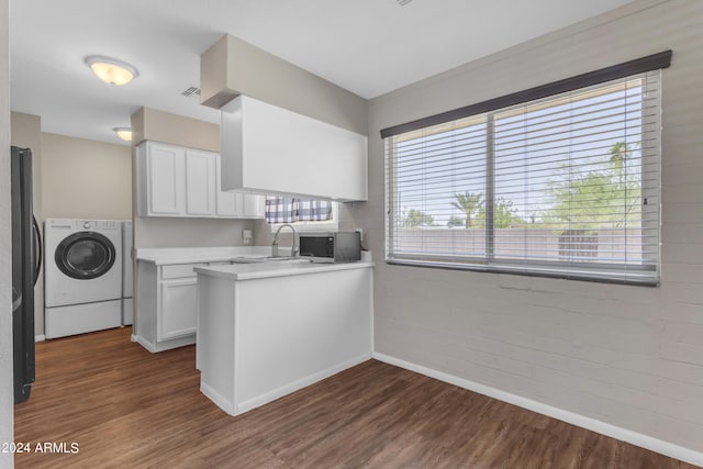 kitchen with sink, kitchen peninsula, washer / dryer, white cabinets, and dark wood-type flooring