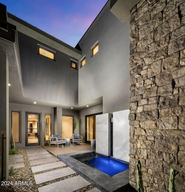 back house at dusk featuring a patio area