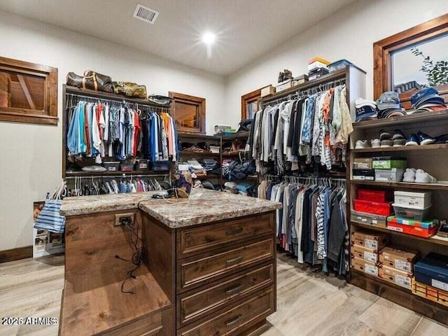 walk in closet with light hardwood / wood-style floors