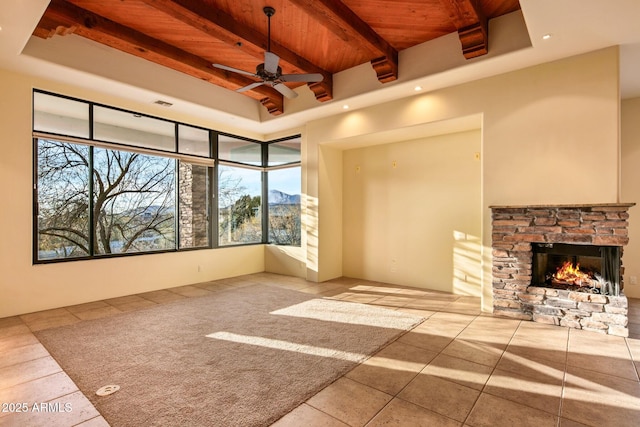 unfurnished living room with beam ceiling, wood ceiling, a tray ceiling, ceiling fan, and a fireplace