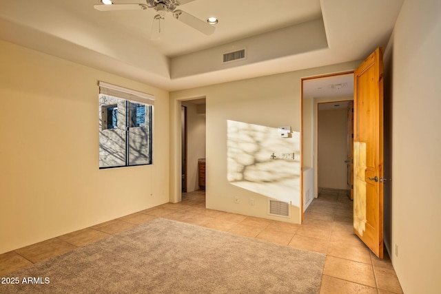 spare room with light tile patterned floors, a tray ceiling, and ceiling fan