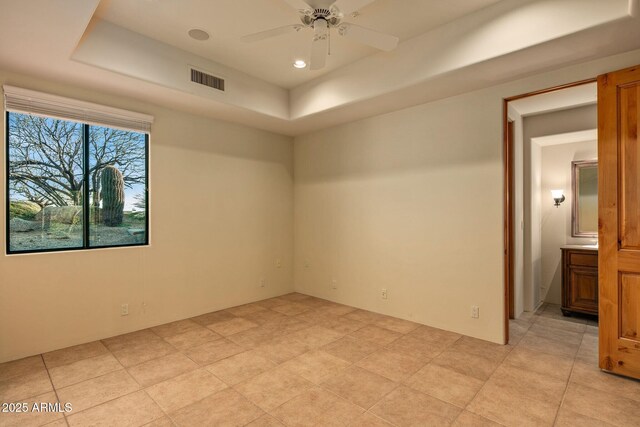 unfurnished room featuring ceiling fan and a raised ceiling