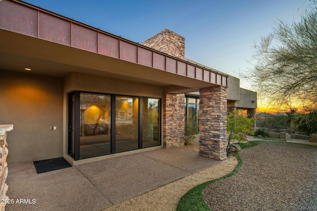 exterior entry at dusk featuring a patio area