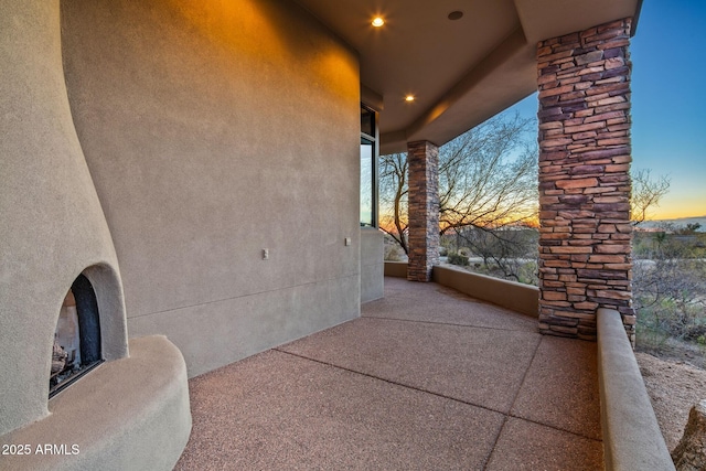 patio terrace at dusk featuring an outdoor fireplace