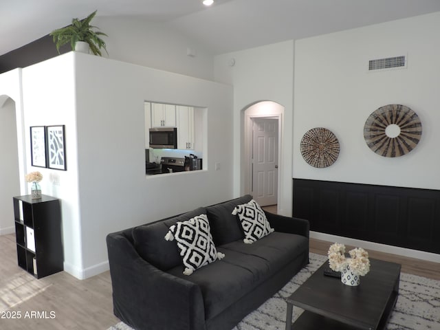 living room featuring light wood-type flooring and vaulted ceiling