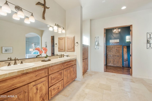 bathroom featuring a sink, double vanity, connected bathroom, and baseboards