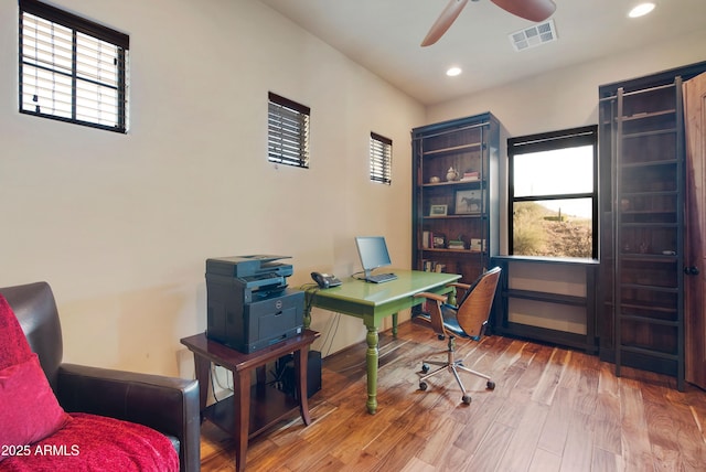 office with a healthy amount of sunlight, ceiling fan, visible vents, and wood finished floors