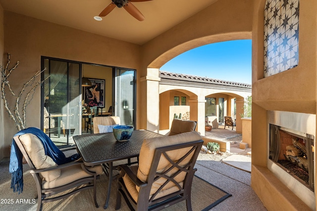 view of patio / terrace featuring a ceiling fan, outdoor dining area, and exterior fireplace