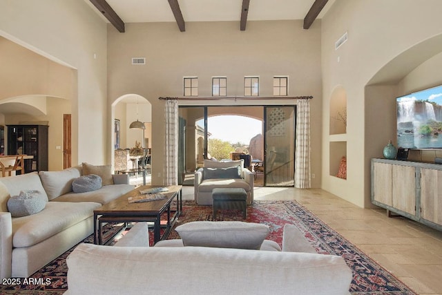 living area with arched walkways, visible vents, beamed ceiling, and a towering ceiling