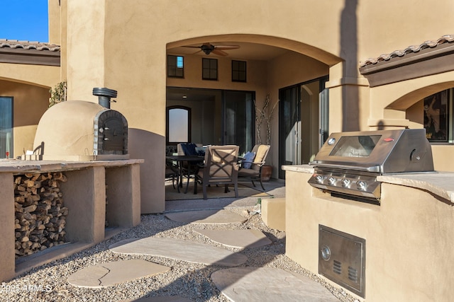 view of patio / terrace with exterior kitchen, outdoor dining area, area for grilling, and a ceiling fan