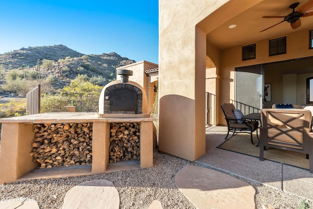 view of patio / terrace featuring ceiling fan, a fireplace, and a mountain view