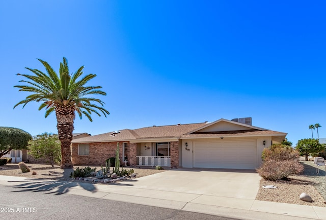 ranch-style house featuring an attached garage, driveway, central AC unit, and brick siding