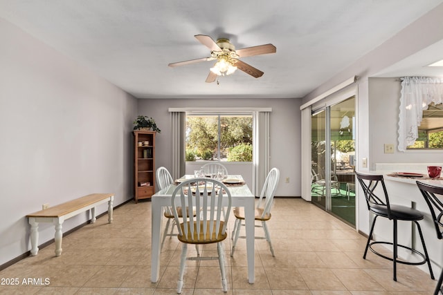 dining space featuring a ceiling fan, baseboards, and light tile patterned floors