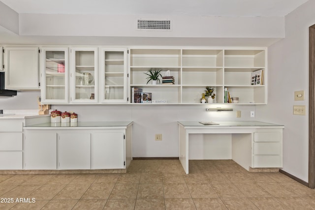 kitchen featuring open shelves, light countertops, visible vents, glass insert cabinets, and white cabinetry