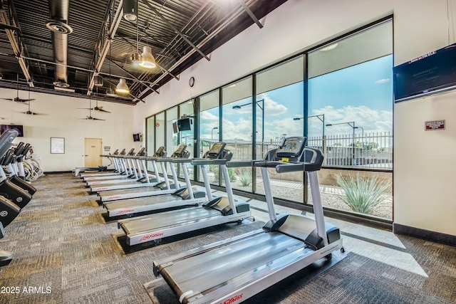 gym with a high ceiling, baseboards, and carpet flooring