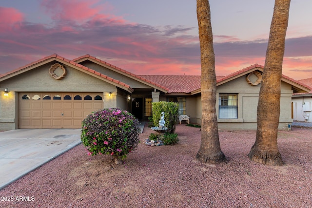 view of front of house with concrete driveway, an attached garage, a tiled roof, and stucco siding