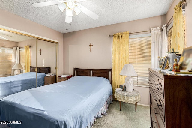 bedroom with a textured ceiling, carpet floors, a closet, and a ceiling fan