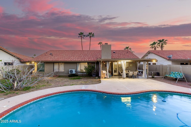 pool at dusk with a fenced in pool, a patio, and fence