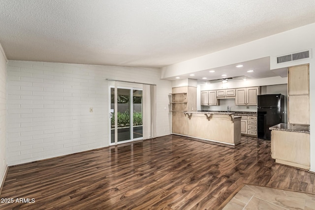5420 N Granite Reef Rd, Scottsdale, AZ 85250 - kitchen featuring freestanding refrigerator, a peninsula, a kitchen breakfast bar, a textured ceiling, and dark wood-style floors