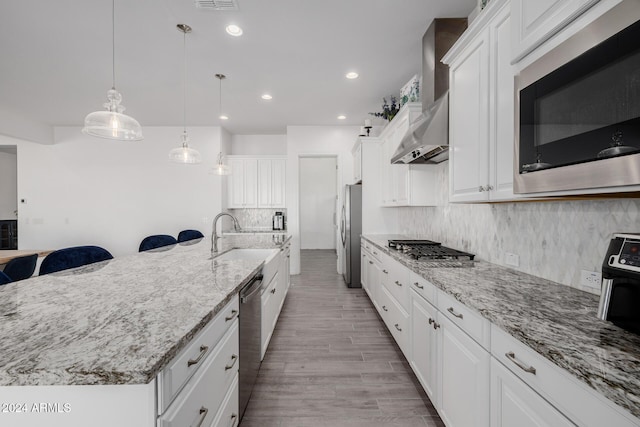 kitchen featuring sink, white cabinetry, stainless steel appliances, and hanging light fixtures