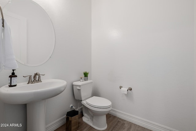 bathroom featuring wood-type flooring, toilet, and sink