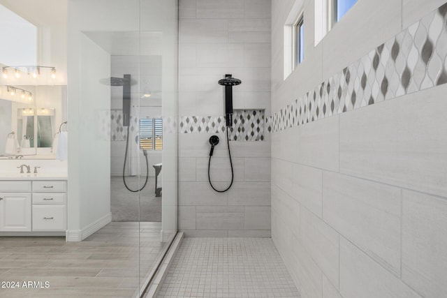 bathroom with a tile shower and vanity