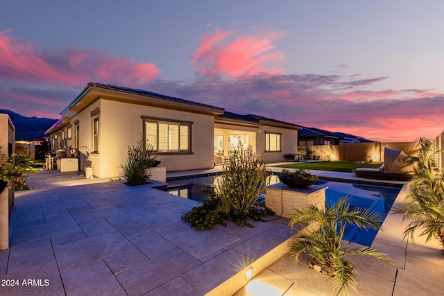 back house at dusk featuring a patio area