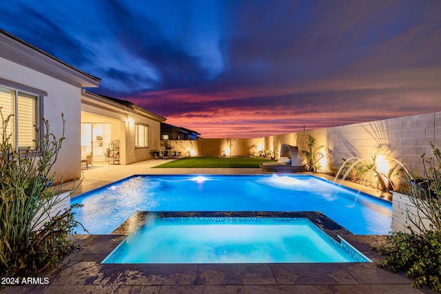 pool at dusk with pool water feature, an in ground hot tub, and a patio