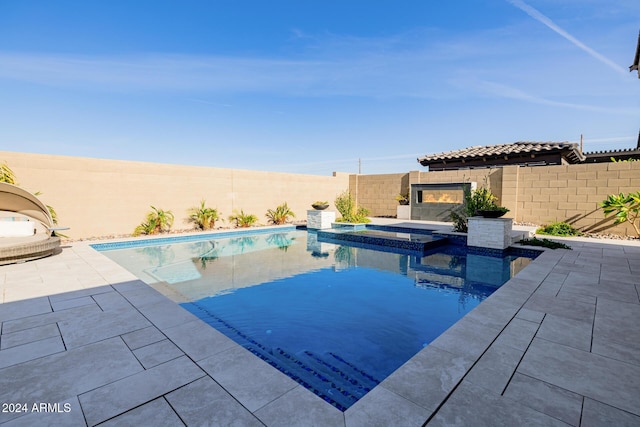 view of swimming pool with a tile fireplace, an in ground hot tub, and a patio