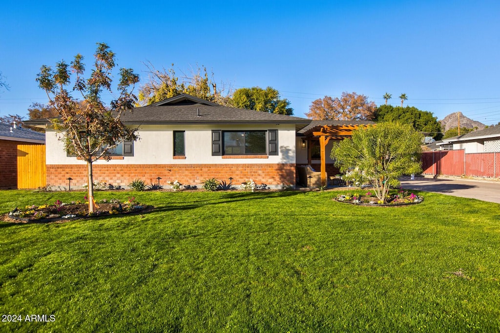 ranch-style home featuring a pergola and a front lawn