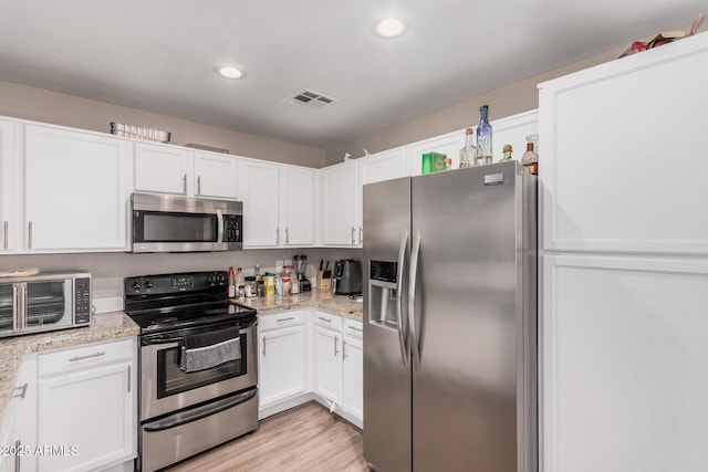 2516 E San Manuel Rd, San Tan Valley, AZ 85143 - kitchen with appliances with stainless steel finishes, white cabinets, recessed lighting, light wood finished floors, and light stone countertops