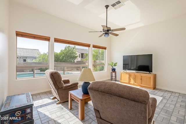 living room featuring brick floor, ceiling fan, baseboards, and visible vents