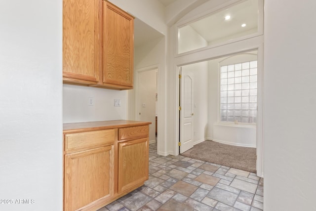 kitchen featuring stone finish floor, light countertops, and baseboards