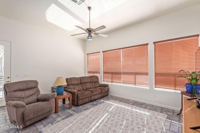 living area with visible vents, baseboards, a ceiling fan, and stone tile flooring
