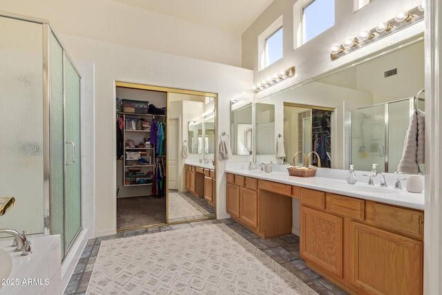 full bath featuring visible vents, a spacious closet, a shower stall, and double vanity