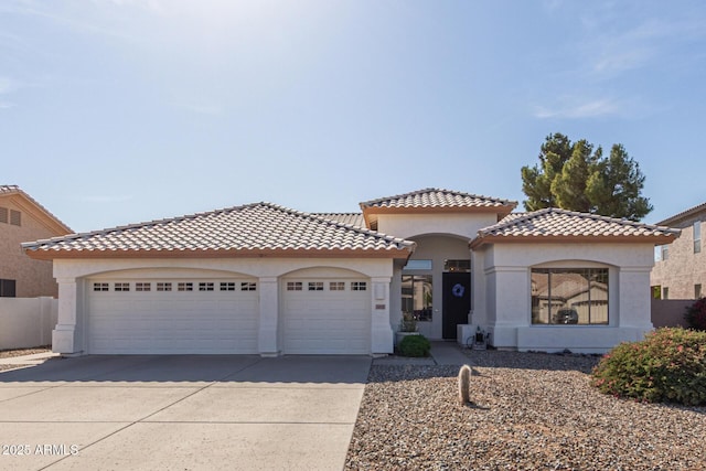 mediterranean / spanish house featuring a tile roof, stucco siding, a garage, and concrete driveway