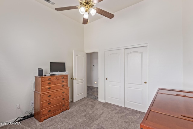 carpeted bedroom with a towering ceiling, a closet, visible vents, and a ceiling fan