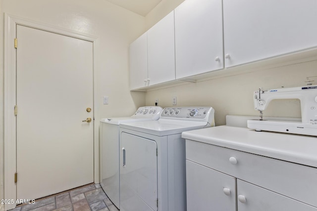 washroom with separate washer and dryer, stone finish floor, and cabinet space