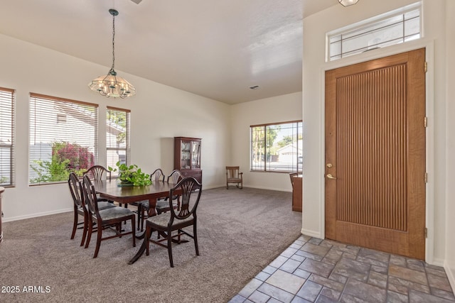 carpeted dining space featuring a chandelier, baseboards, and stone finish flooring
