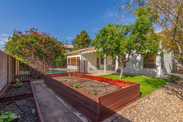back of property featuring stucco siding, fence private yard, and a vegetable garden