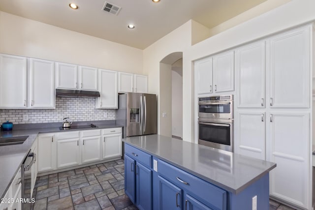 kitchen featuring white cabinets, under cabinet range hood, visible vents, stainless steel appliances, and arched walkways