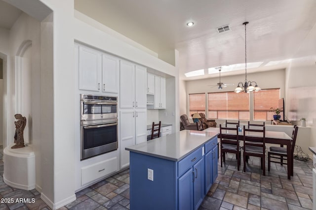 kitchen with white cabinets, visible vents, double oven, blue cabinets, and hanging light fixtures