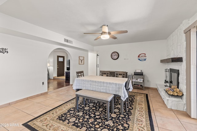 bedroom featuring ceiling fan, light tile patterned floors, and a fireplace