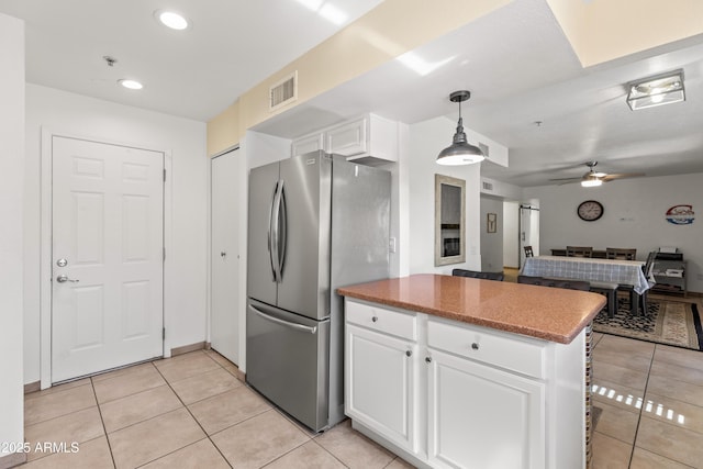 kitchen featuring light tile patterned floors, stainless steel fridge, ceiling fan, white cabinetry, and decorative light fixtures