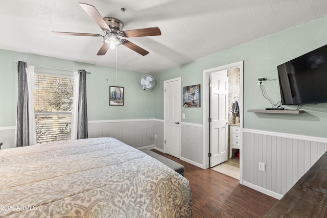 bedroom featuring ceiling fan, ensuite bath, dark wood-type flooring, and a textured ceiling