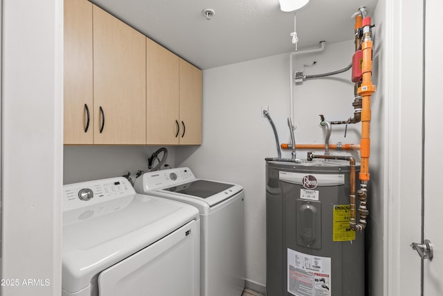 clothes washing area with cabinets, washer and clothes dryer, and water heater