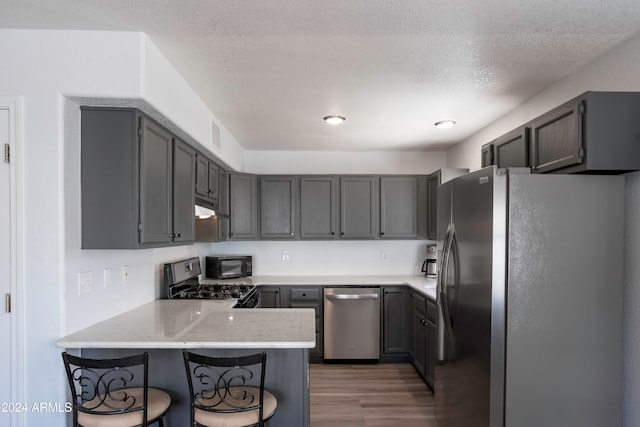 kitchen with black appliances, gray cabinetry, kitchen peninsula, and dark hardwood / wood-style floors