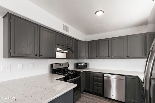 kitchen featuring stainless steel appliances, light stone countertops, and dark hardwood / wood-style floors