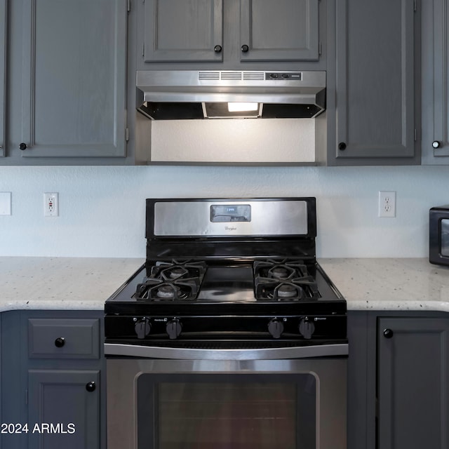 kitchen featuring gray cabinets, extractor fan, stainless steel gas stove, and light stone counters