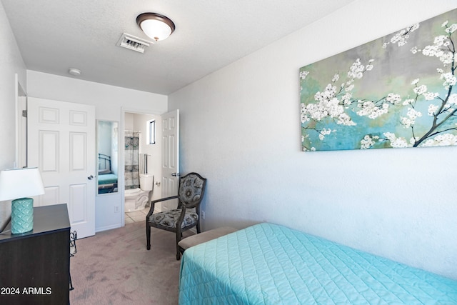 bedroom featuring a textured ceiling, carpet flooring, and ensuite bath